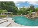 Large backyard swimming pool with a waterfall, slide, and lush greenery, ideal for outdoor entertainment at 8410 Kenavis Pl, Odessa, FL 33556