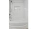 White bathtub with shower head and built-in shelf in a tiled bathroom at 9418 W Park Village Dr # 105, Tampa, FL 33626