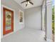 Covered porch area featuring a red door, a ceiling fan, and decorative columns at 9418 W Park Village Dr # 105, Tampa, FL 33626