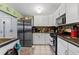 Functional kitchen with stainless steel appliances, sleek white cabinets, and tile backsplash at 9602 N Rome Ave, Tampa, FL 33612