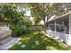 Spacious backyard featuring green lawn, mature trees, and a cozy screened-in porch for outdoor relaxation at 10095 Oakhurst Rd, Seminole, FL 33776