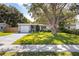 Charming single-story home with a lush front yard and mature tree, American flag and inviting curb appeal at 10095 Oakhurst Rd, Seminole, FL 33776