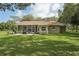 Back exterior of a home with screened in patio, brick pavers, and large grassy yard at 10614 Hudson Ave, Hudson, FL 34669