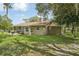 Back exterior view of a home with a screened in patio, brick pavers, and surrounding large grassy yard at 10614 Hudson Ave, Hudson, FL 34669