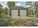 Exterior view of a two-door gray garage with a gravel area in front and lawn on the sides at 10614 Hudson Ave, Hudson, FL 34669