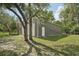 Side exterior view of a two-door gray garage with a white service door and grassy lawn at 10614 Hudson Ave, Hudson, FL 34669