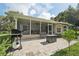 Spacious screened-in patio with brick pavers, wicker furniture, and a grill at 10614 Hudson Ave, Hudson, FL 34669