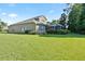 Exterior view of the home's backyard featuring a green lawn, screened-in patio, and lush landscaping at 10751 Tavistock Dr, Tampa, FL 33626