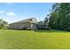 Exterior view of the home's backyard featuring a green lawn, screened-in patio, and lush landscaping at 10751 Tavistock Dr, Tampa, FL 33626