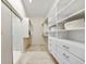 Walk-in closet with built-in white storage system with shelving, drawers, and a sliding door to bathroom at 10751 Tavistock Dr, Tampa, FL 33626