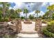 Outdoor fire pit area with stone pillars, seating, and surrounded by palm trees at 11039 Calluna Dr, Odessa, FL 33556