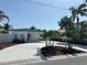 Stylish single-story home with blue trim, lush palm trees, and a wide driveway leading to a carport at 11110 1St E St, Treasure Island, FL 33706