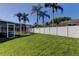 Large backyard with mature palm trees and a vinyl fence surrounding the home with a screened lanai at 12004 Plantain Ct, Tampa, FL 33635