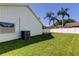 This home features a spacious backyard with lush grass and mature palm trees, ideal for outdoor activities at 12004 Plantain Ct, Tampa, FL 33635