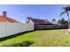 Large grassy backyard with a wooden fence and a white vinyl fence surrounding the entire property at 12004 Plantain Ct, Tampa, FL 33635