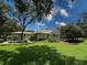 Expansive backyard with mature trees, lush lawn, screened enclosure, and meticulously maintained landscaping at 13807 Eagles Rock Ct, Hudson, FL 34667