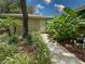 Exterior view of the home features mature trees, a garden and sidewalk leading to the front door at 13807 Eagles Rock Ct, Hudson, FL 34667