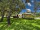 Side view of house with three car garage, bordered by beautiful landscaping and mature trees at 13807 Eagles Rock Ct, Hudson, FL 34667
