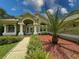 Beautiful home showcasing meticulous landscaping with a palm tree and column-supported front porch at 13807 Eagles Rock Ct, Hudson, FL 34667