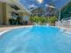Large, screened in pool surrounded by well-maintained patio and lush tropical plants at 13807 Eagles Rock Ct, Hudson, FL 34667