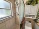 Tiled shower with glass door, cabinet, and window for natural light at 13807 Eagles Rock Ct, Hudson, FL 34667