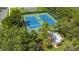 Aerial view of two vibrant blue and green tennis courts with well-maintained landscaping at 13807 Eagles Rock Ct, Hudson, FL 34667