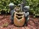 Outdoor decorative fountain sculpture with boy and girl figures on mulch in a backyard landscape at 13807 Eagles Rock Ct, Hudson, FL 34667
