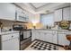 Bright kitchen with white cabinets, appliances, tile backsplash, and black and white accessories at 147 Bluff View Dr # 105, Belleair Bluffs, FL 33770