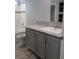 Bathroom with a granite vanity and grey cabinets with a tiled shower and tub at 15591 Charmwood Dr, Hudson, FL 34667