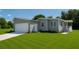 Charming gray home featuring an attached garage and a well-maintained, expansive green lawn at 15591 Charmwood Dr, Hudson, FL 34667