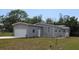 Well-maintained single-Gathering home featuring a grey facade, attached garage, and front lawn at 15591 Charmwood Dr, Hudson, FL 34667