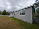 Exterior side view of home showing light gray vinyl siding and front porch at 15591 Charmwood Dr, Hudson, FL 34667