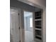 Hallway view showing open door to bedroom and built in shelving on gray wall at 15591 Charmwood Dr, Hudson, FL 34667