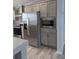 Modern kitchen featuring stainless steel refrigerator, built-in microwave, and gray cabinets at 15591 Charmwood Dr, Hudson, FL 34667