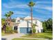 Charming two-story home featuring a well-maintained lawn, a blue garage door, and palm tree landscaping at 1669 Ludington Ave, Wesley Chapel, FL 33543