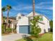 Two-story home featuring verdant lawn, mature palms, neutral stucco, and a teal garage door at 1669 Ludington Ave, Wesley Chapel, FL 33543