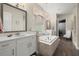 Elegant bathroom with a soaking tub, chandelier, wood-look flooring, and views to walk-in closet at 16938 Scuba Crest St, Wimauma, FL 33598