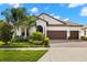 Charming home boasts a three-car garage, terracotta roof, and lush landscaping at 16938 Scuba Crest St, Wimauma, FL 33598