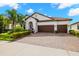 Charming home boasts a three-car garage, terracotta roof, lush landscaping, and a brick paved driveway at 16938 Scuba Crest St, Wimauma, FL 33598