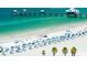 Picturesque beach scene with a pier, turquoise water, white sand, and rows of beachgoers with blue umbrellas at 1861 Royal Oak E Pl, Dunedin, FL 34698
