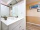 Bathroom featuring a white vanity with sink, large mirror, and access to the hallway at 1861 Royal Oak E Pl, Dunedin, FL 34698