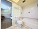 Well-lit bathroom with tiled floors, a toilet, and a tub, offering a view to the bedroom at 1861 Royal Oak E Pl, Dunedin, FL 34698