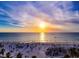 Stunning sunset over a white sand beach dotted with palm trees and beachgoers, offering a serene coastal experience at 1861 Royal Oak E Pl, Dunedin, FL 34698