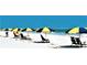 Relaxing beach scene with blue and yellow umbrellas, lounge chairs, and calm, turquoise water at 1861 Royal Oak E Pl, Dunedin, FL 34698