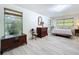Bright bedroom with wood look floors, windows and dresser at 1861 Royal Oak E Pl, Dunedin, FL 34698