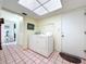Bright laundry room featuring a skylight, washer and dryer, and tile flooring at 1861 Royal Oak E Pl, Dunedin, FL 34698