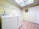 Bright laundry room featuring a skylight, washer and dryer, and tile flooring at 1861 Royal Oak E Pl, Dunedin, FL 34698