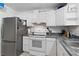 Kitchen featuring stainless steel refrigerator, white cabinets, granite countertops, and tiled flooring at 1881 N Hercules Ave # 1501, Clearwater, FL 33765
