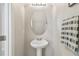 Stylish half-bathroom featuring a pedestal sink, oval mirror, modern faucet, and gray/white striped towel at 21284 Southern Charm Dr, Land O Lakes, FL 34637