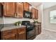 The kitchen is equipped with modern black appliances, granite countertops, and rich wooden cabinets at 21284 Southern Charm Dr, Land O Lakes, FL 34637